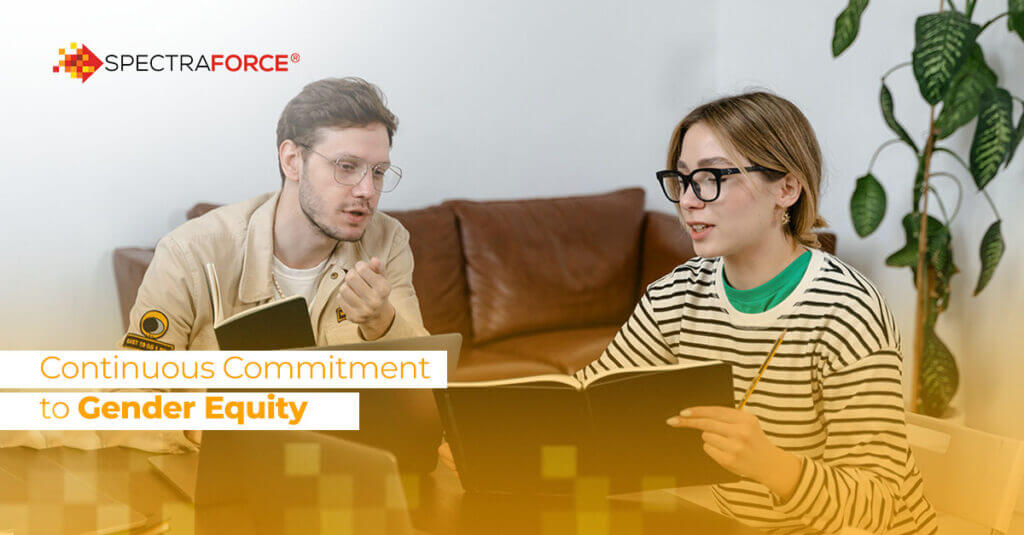 Two colleagues are engaged in a discussion while holding notebooks. They appear to be sitting in a modern office with a couch and large houseplant in the background. The SpectraForce logo is in the top left corner, with the text "Continuous Commitment to Gender Equity" displayed below.