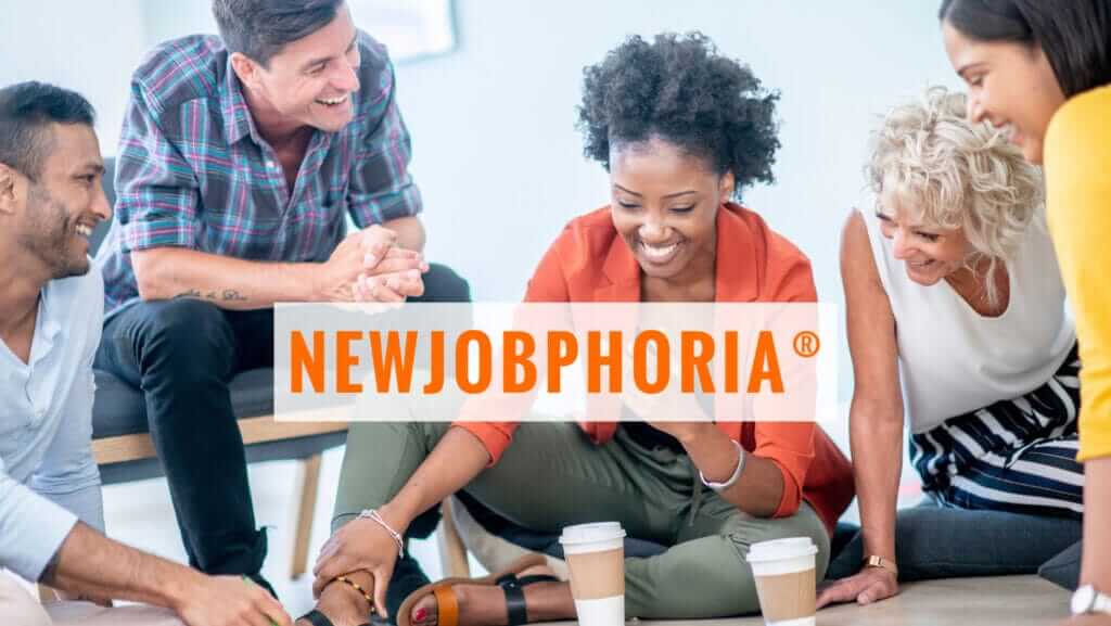 A group of diverse and happy people sits casually in a circle, sharing a laugh. The word 'NEWJOBPHORIA®' is displayed prominently in bold orange text over the center of the image, prompting curiosity: "WHAT DOES NEWJOBPHORIA® MEAN?" Two cups of coffee rest on the floor in front of them.