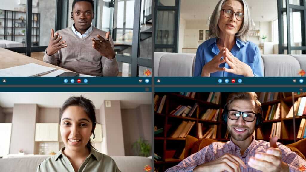 A video conference with four participants. Top left shows a man speaking with hand gestures, top right features an inspirational woman in glasses speaking, bottom left displays another smiling woman, and bottom right shows a man wearing glasses and headphones, smiling while speaking.