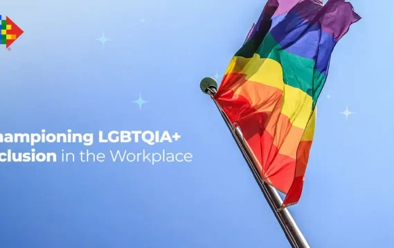Rainbow pride flag waving under blue sky, promoting LGBTQIA+ inclusion and diversity in the workplace.